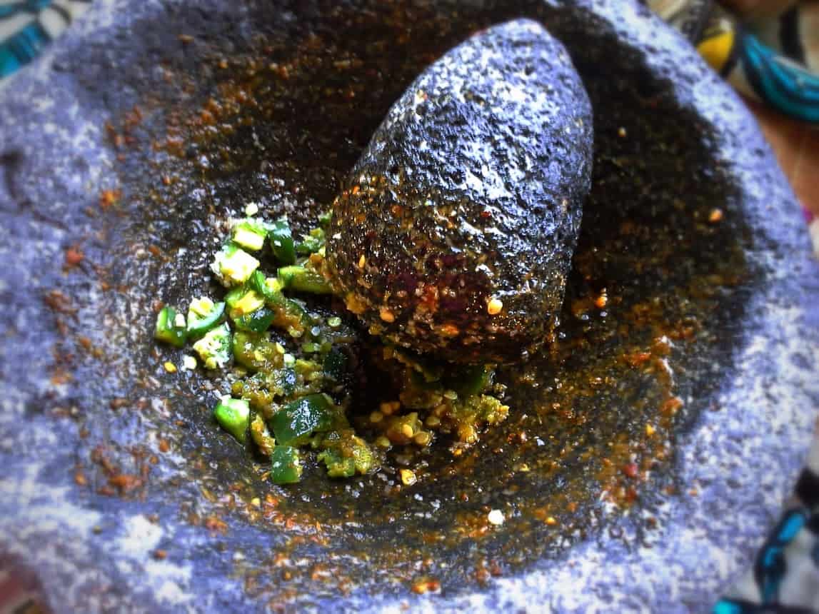 In that same molcajete from the chile piquin salsa, continue to build flavors for the guacamole.