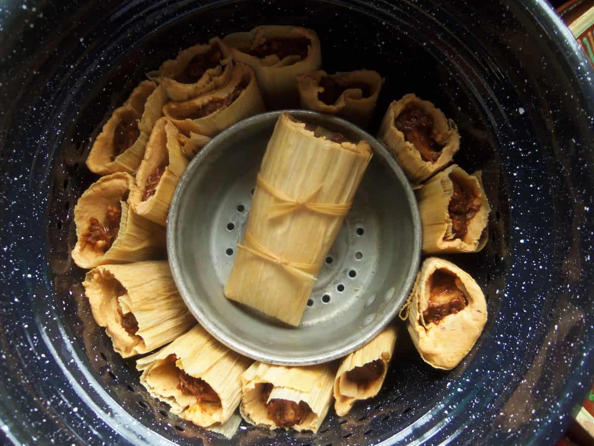 When I don't have enough tamales to fit the steamer pot, I will insert a heat safe bowl or small pot in the center. This will keep the tamales from falling over and becoming mis-shapen while they steam.