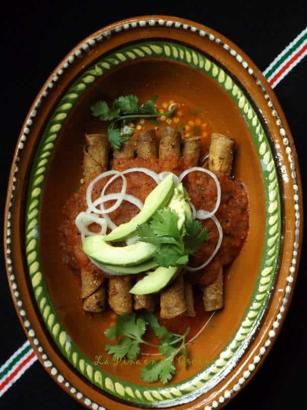Codzitos in an oval Mexican dish garnished with salsa, onion and avocado