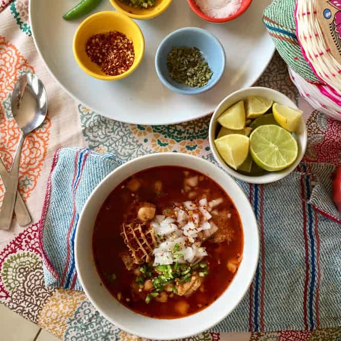 menudo rojo in large bowl with garnishes in smaller bowls