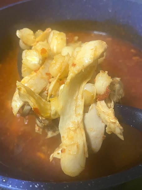 big spoonful od red chile chicken pozole out of the pot