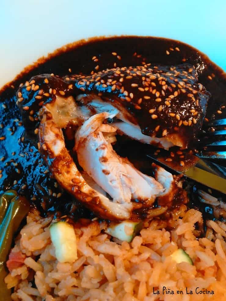 Sliced open chicken mole plated with rice. 