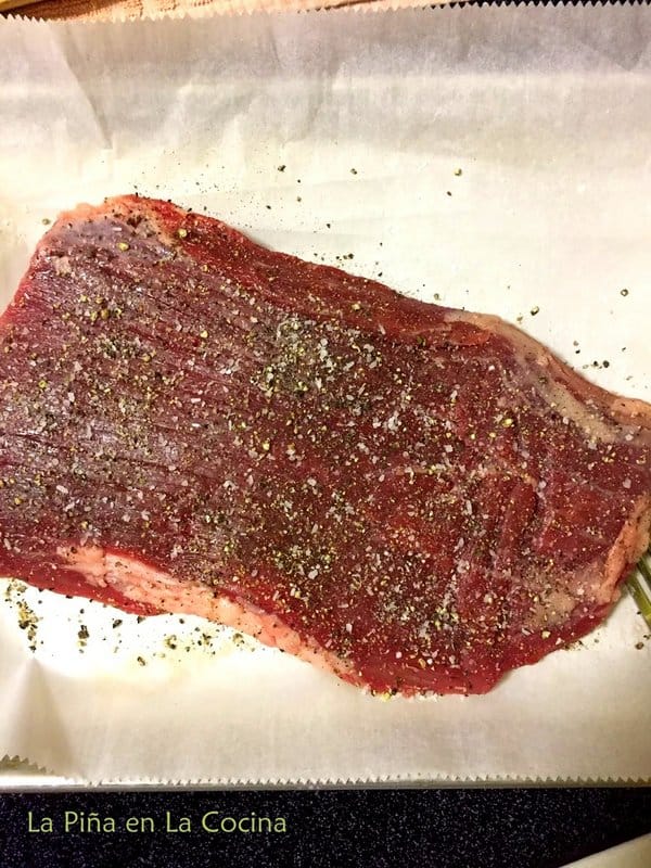 Uncooked flank steak seasoned with salt and pepper