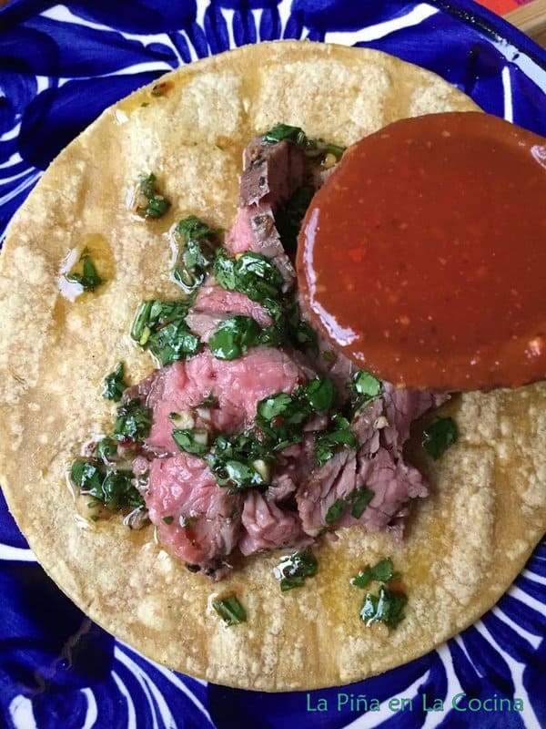 Flan steak taco with spoonful of toasted chile de arbol salsa on spoon