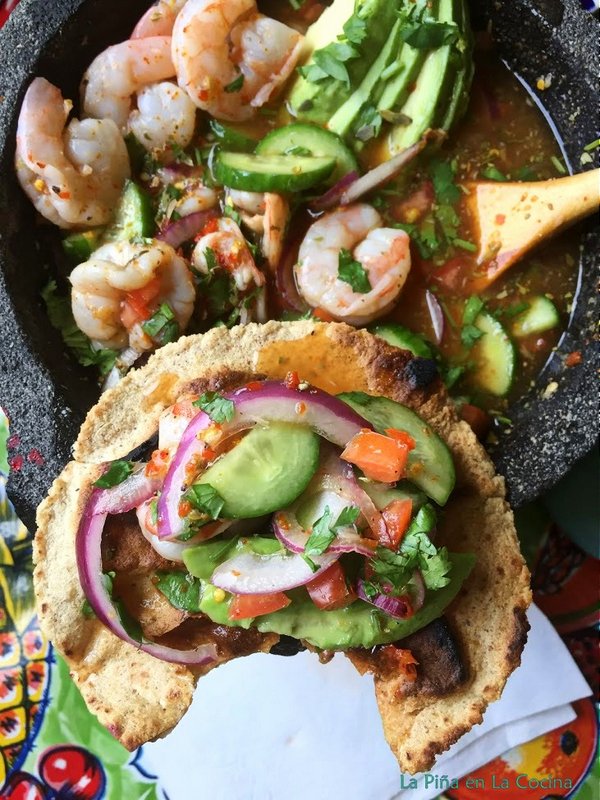 Chile piquin shrimp aguachile on corn tostada with molcajete in the back round