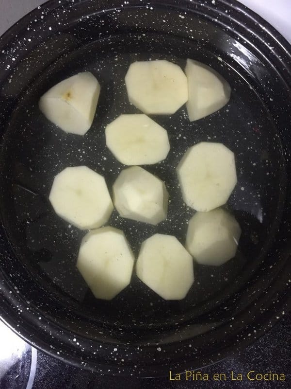 Peeled potato sections in water ready to cook
