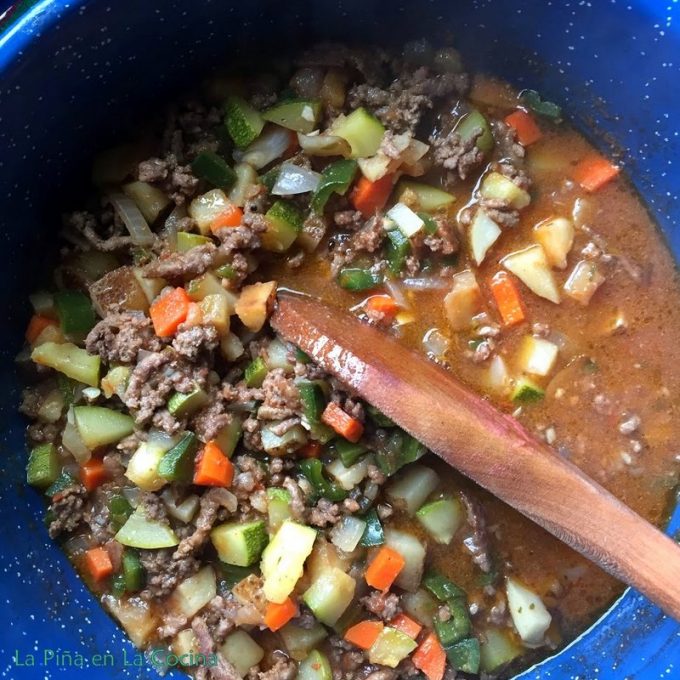 Top view of beef picadillo in the pot with wooden spoon