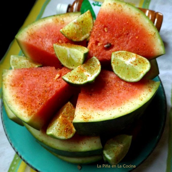 Watermelon sliced into thick wedges, seasoned with chile limon powder and lime
