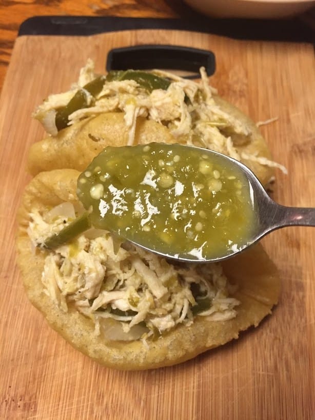 Chicken puffy tacos with salsa verde on a spoon