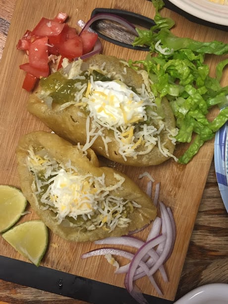 Two chicken puffy tacos with fresh garnishes