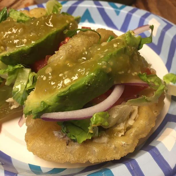 Puffy chicken taco garnished with avocado wedge and salsa verde