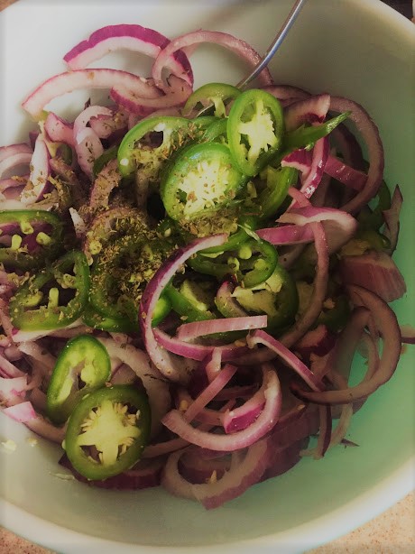 Mixing onions with jalapeno and oregano in a bowl