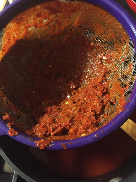 Straining the red chile sauce