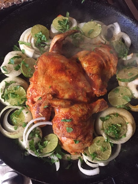 Butterflied chicken seared and basted with chile sauce. Aromatics and lime, cilantro. Ready for the oven.