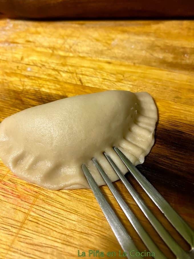 Using a fork to seal the empanada edges