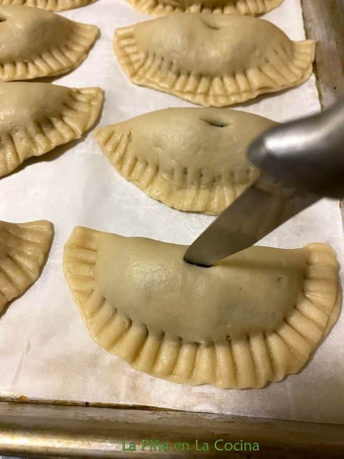 Piercing the tops of empanadas with a knife