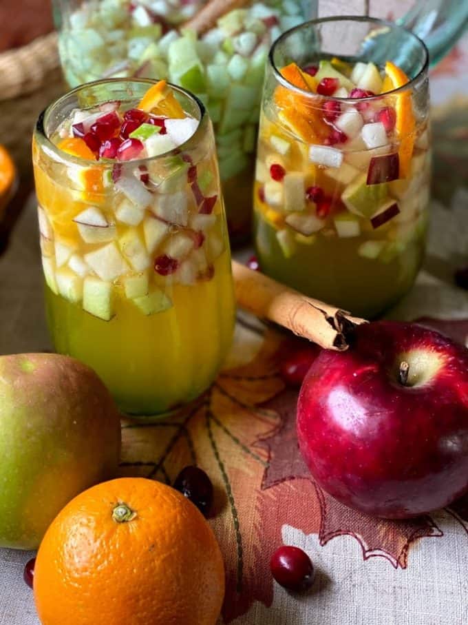 two glasses of fall sangria with apples, orange and cinnamon stick