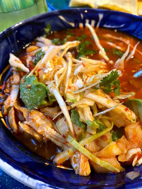 close up of chicken pozole with fresh garnishes