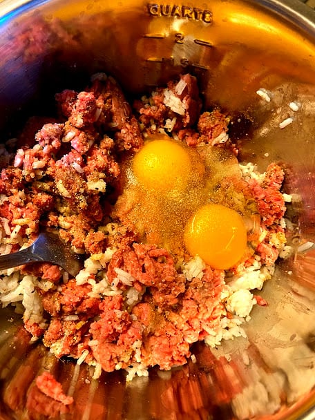 Mixing the ground beef with raw eggs, rice and spices