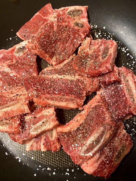 Seasoned beef flanken short ribs in saute pan