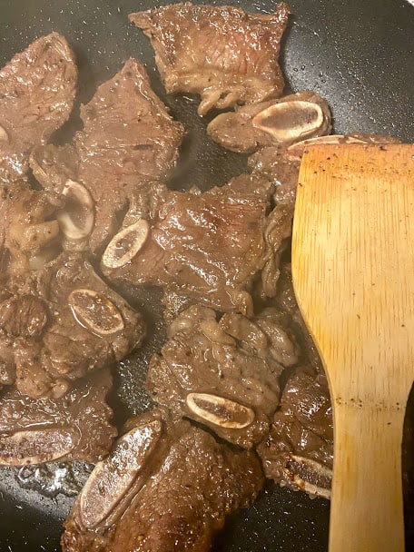 Searing the beef with a wooden spoon in a nonstick pan