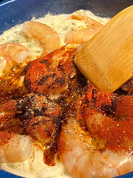 Spices being added to shrimp in butter before stirring and combining