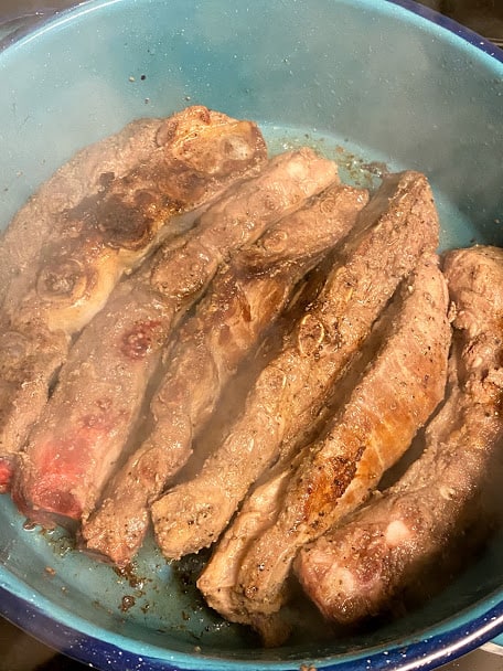 Searing seasoned ribs in large pan