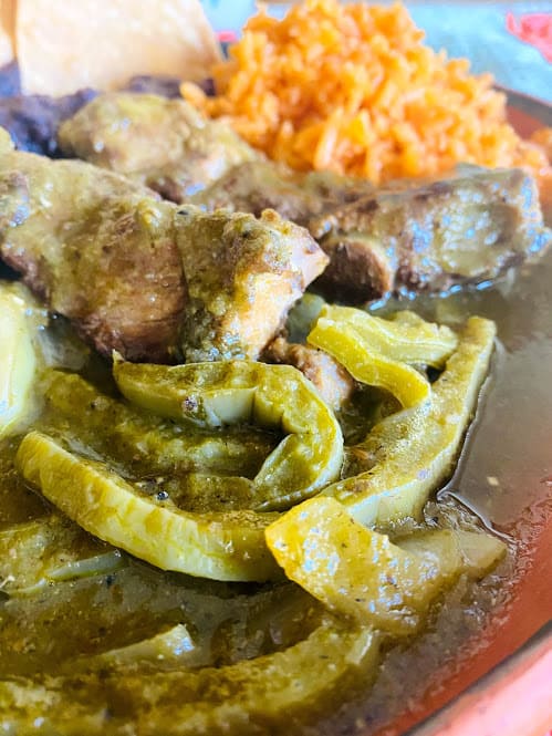 close up o pork ribs with cactus in salsa verde. Rice and beans on the side 