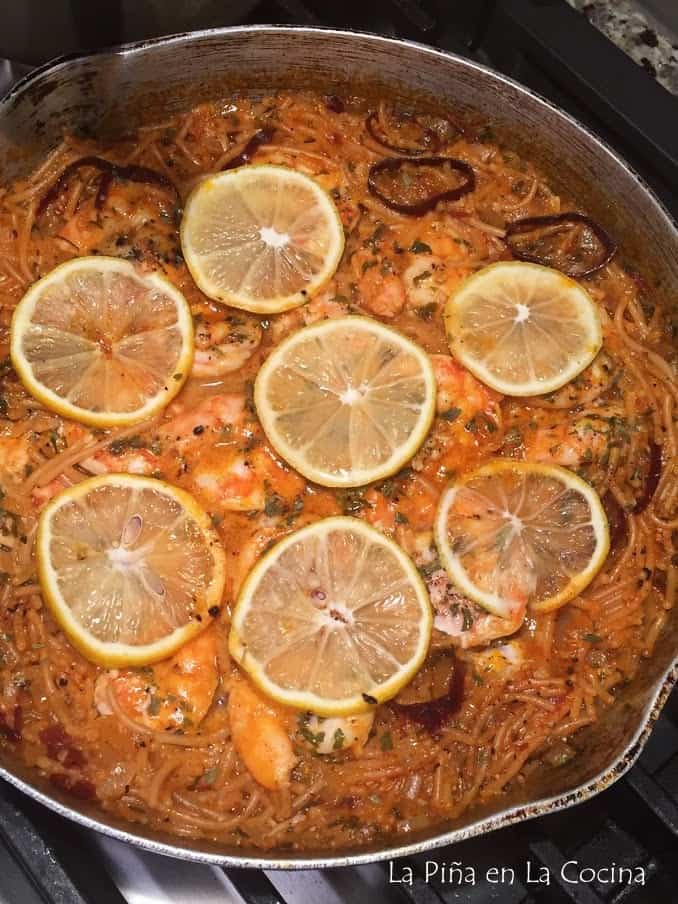 close up of cooked fideo dish in skillet, with lemon slices