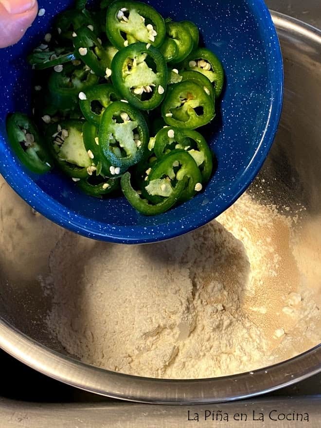 Adding fresh jalapeños to bread ingredients in bowl