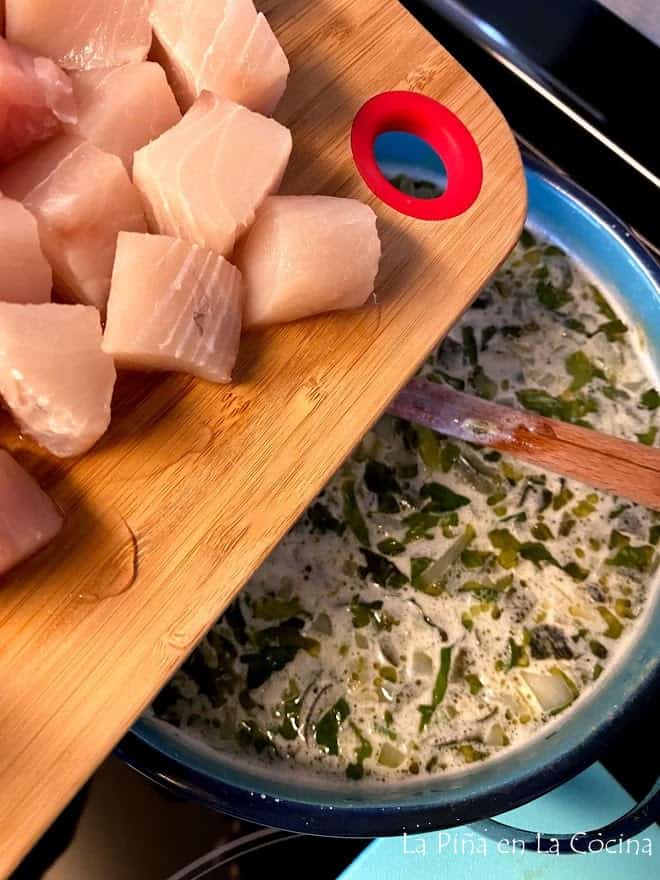 Adding cubed white fish to warm chowder base with vegetables
