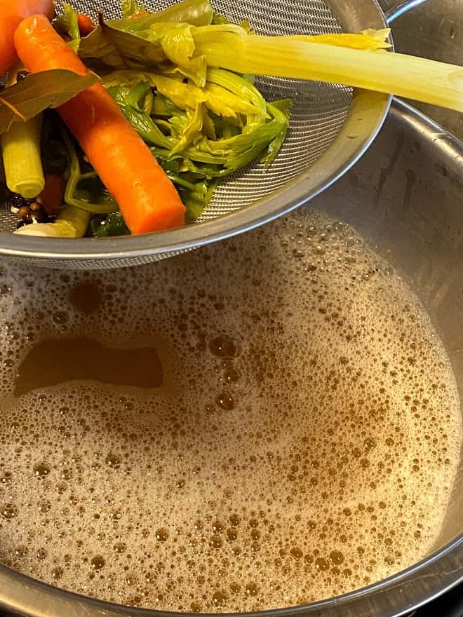 Straining the solids out of broth with wire mesh strainer