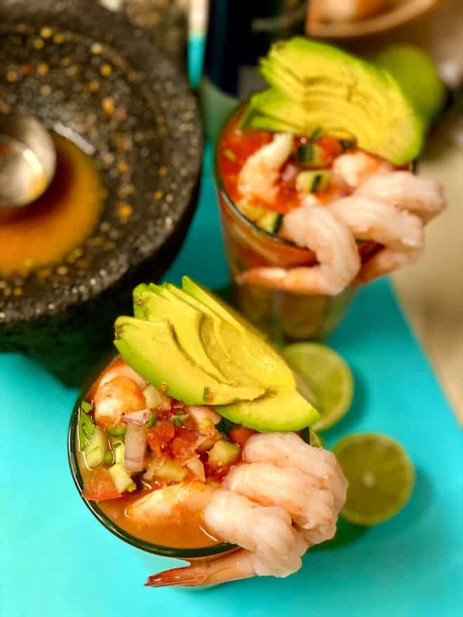 top view of 2 glasses filled with shrimp cocktail garnished with avocado and shrimp on the rim
