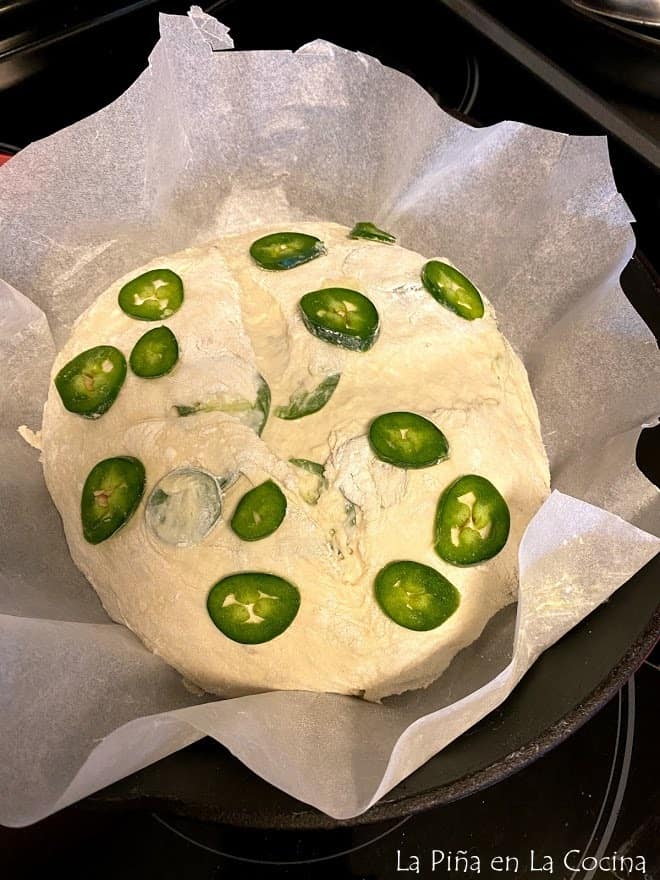 Jalapeño loaf unbaked on parchment paper in a deep cast iron skillet ready for the oven