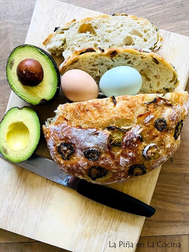 sliced jalapeño loaf on cutting board with sliced avocado and fresh eggs with knife on the side