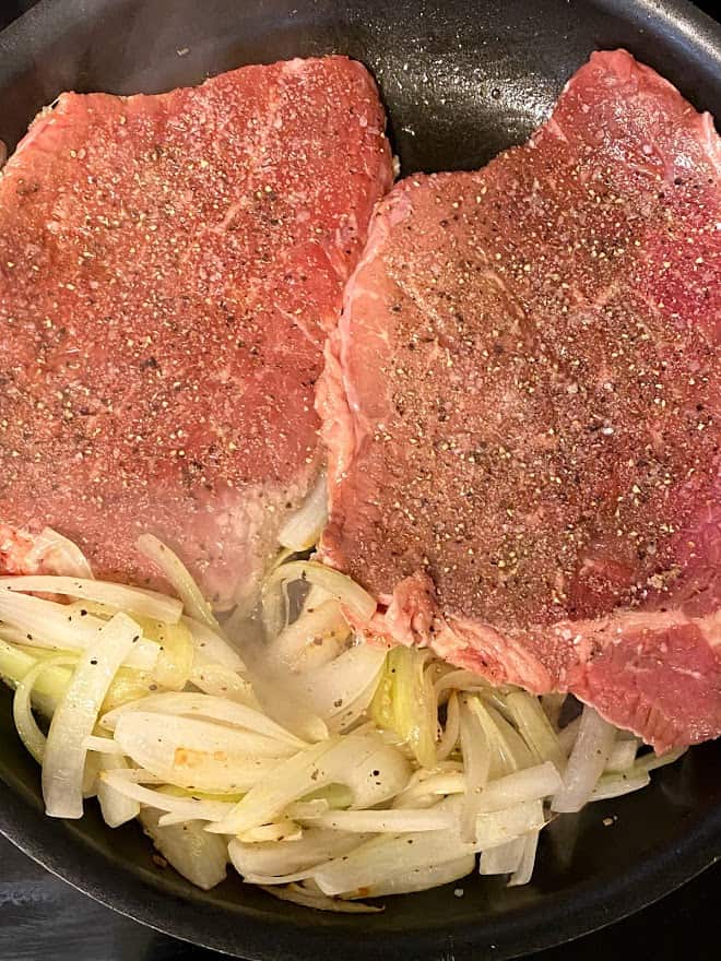 close up of seasoned top round steaks with sauteed onions
