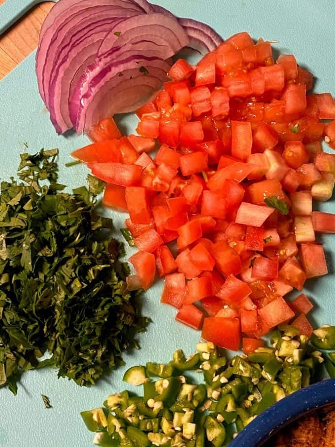 fresh ingredients on cutting board, tomato, onion, cilantro, serrano pepper. Everything chopped