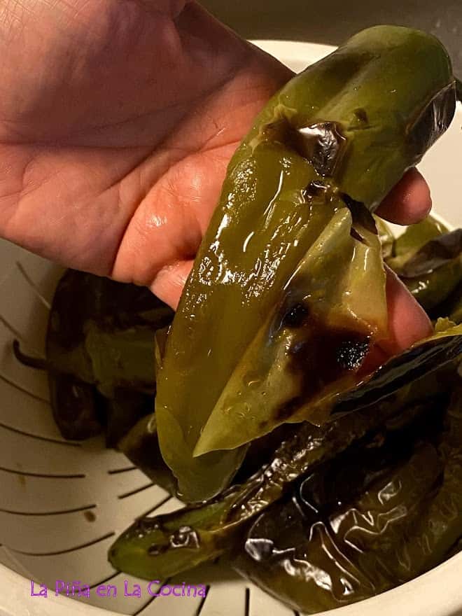 peeling the blistered skins off of the green chile pods