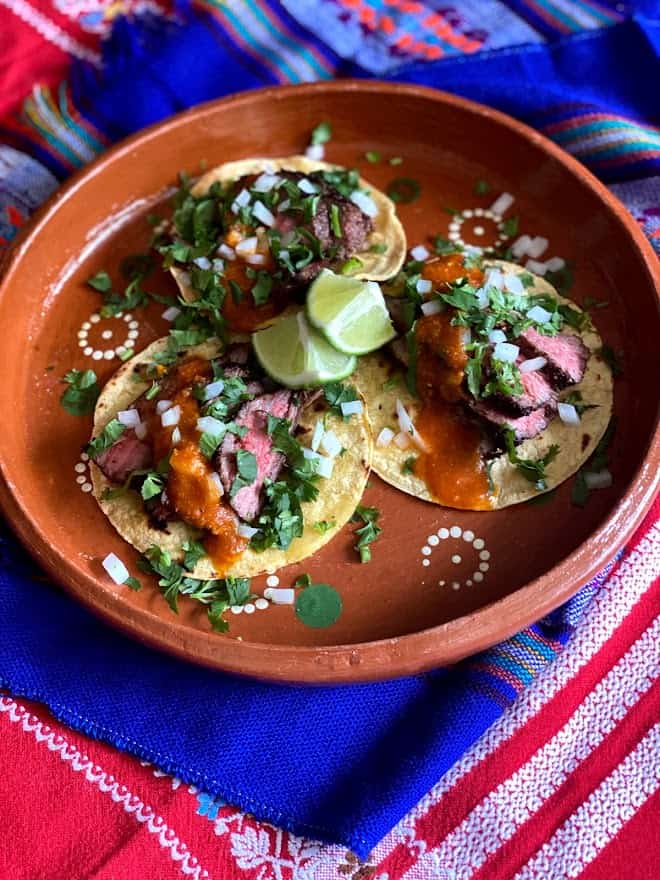 Three flank sterak tacos on Mexican clayware plate
