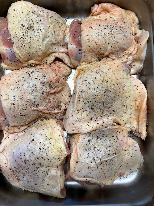 Chicken thighs uncooked seasoned with salt and pepper