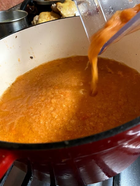 Pouring blended tomato sauce into dutch oven pot