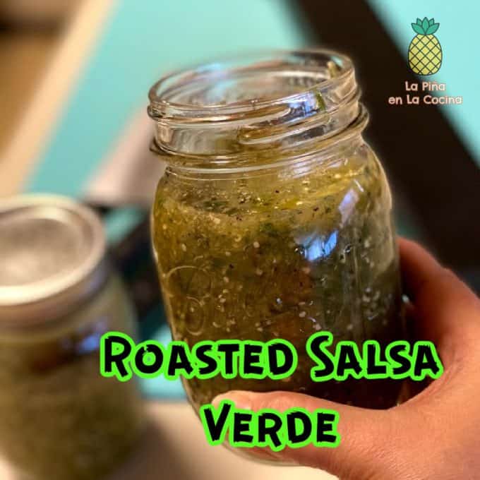 holding an open jar of roasted salsa verde with title-text 