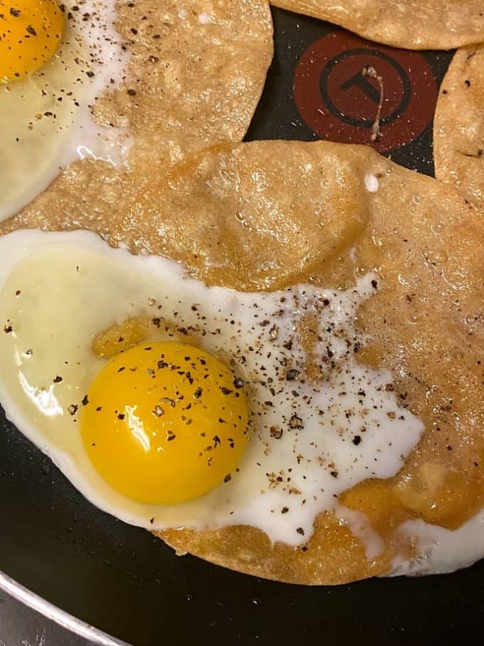 sunny side up eggs cooking on top of fried corn tortilla