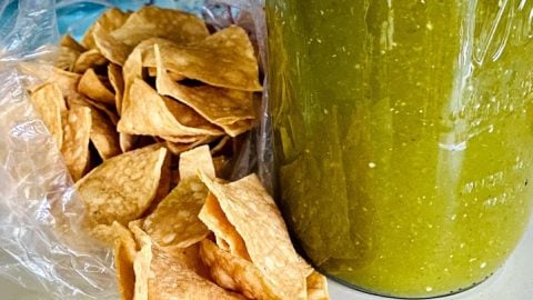 salsa verde in a tall mason jar with chips on the side