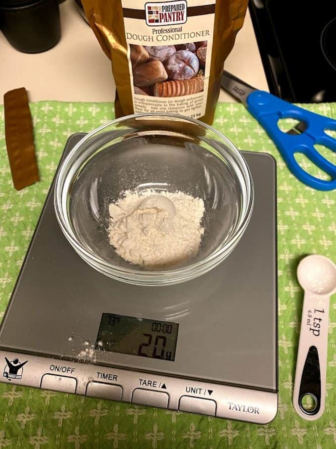 weighing out dough conditioner in a small bowl on scale