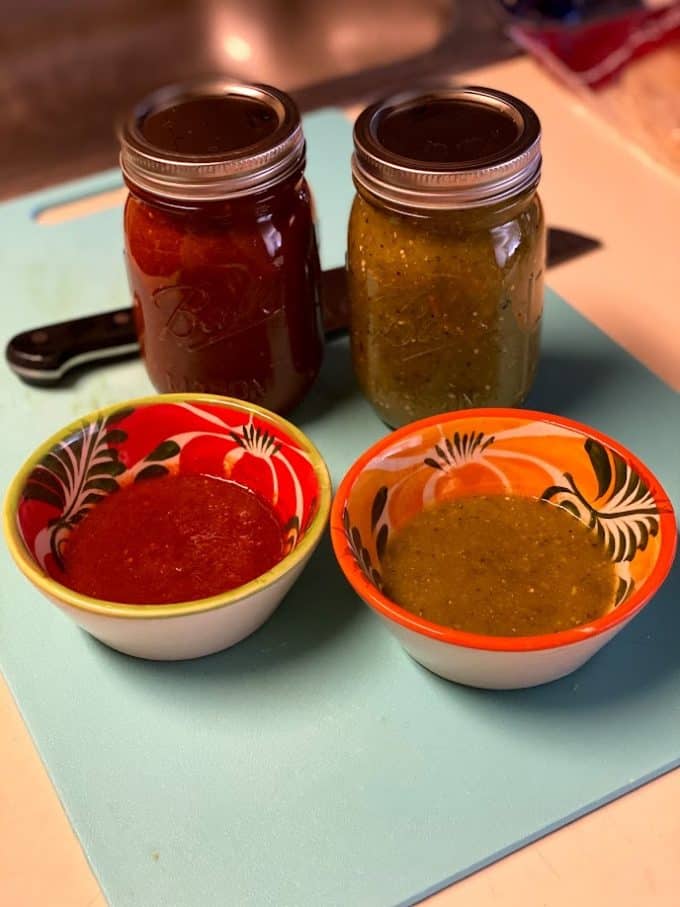Red and green salsa in jars and in small bowls