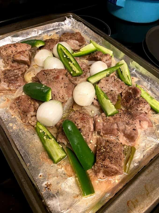 after first hour of roasting, uncovered carnitas with onions and jalapeños added