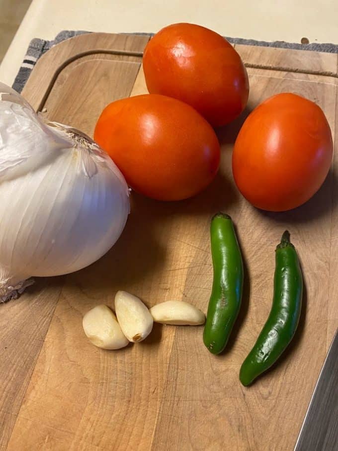 tomatoes, serrano peppers, onion and garlic on cutting board