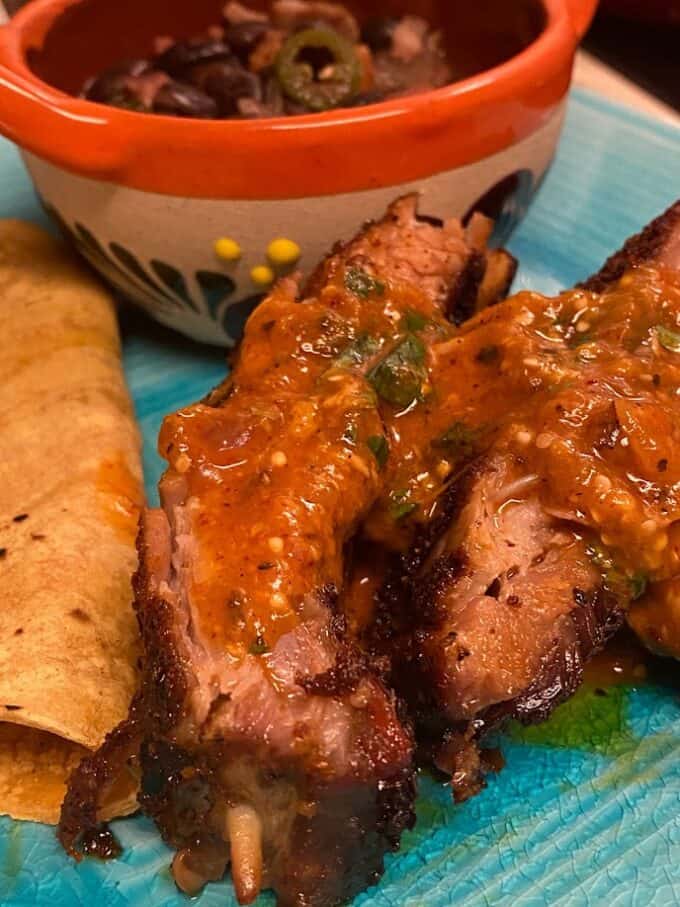 close up of pork ribs plated with a spicy salsa