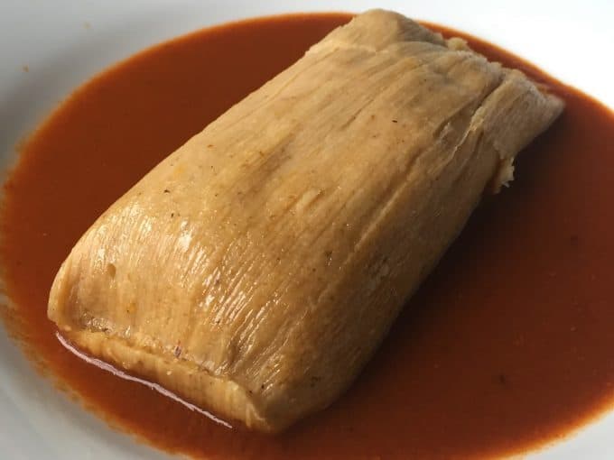 Giant tamal served over consomme in shallow bowl